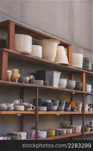 Many various terracotta plant pots on wooden shelf beside the old gypsum board wall in vintage tone style and vertical frame