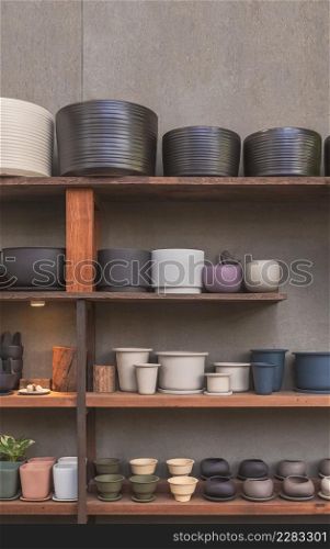 Many various terracotta plant pots on wooden shelf with gray gypsum board wall in vintage tone style and vertical frame