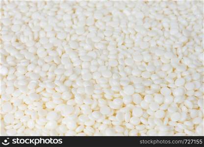 Many white grains of remelt plastic pellets as background