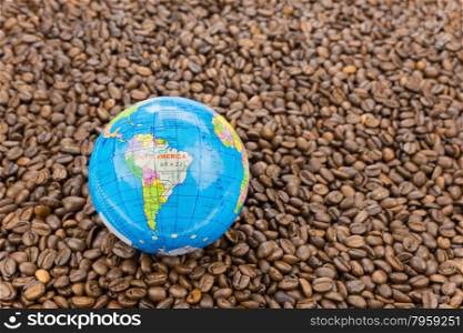 Many whole coffee beans with South America on little globe