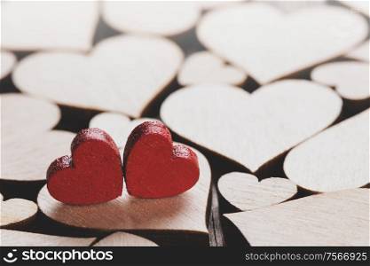 Many wooden colorless hearts background, two red special ones true love concept. Wooden hearts background