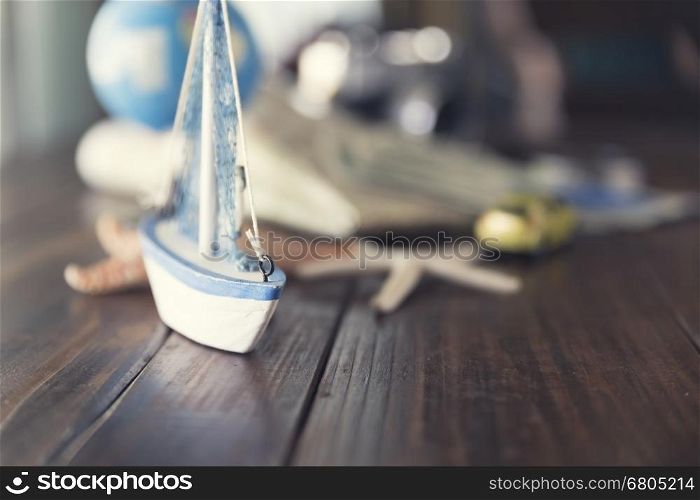 map, globe, ship and car figurine, starfish, banknote, camera on wooden table for use as trip vacation traveling concept (vintage tone and selected focus)