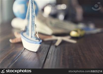 map, globe, ship and car figurine, starfish, banknote, camera on wooden table for use as trip vacation traveling concept (vintage tone and selected focus)