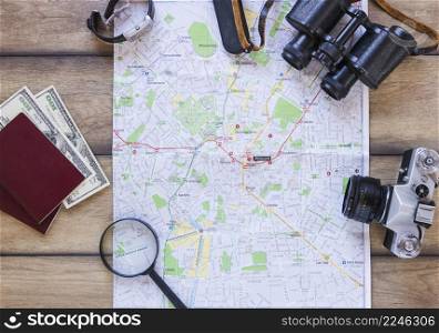 map passport banknotes magnifying glass camera binoculars wrist watch wooden backdrop