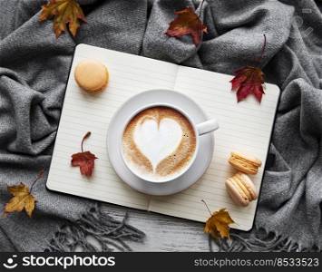 Maple leaves, notebook, coffee cup and scarf. Autumn or Winter concept. Flat lay, top view