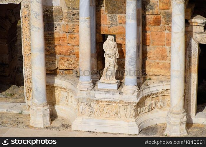 Marble statues at the columns of the amphitheater in Hierapolis, Turkey. Ancient antique amphitheater in the city of Hierapolis in Turkey. Steps and antique statues with columns in the amphitheater. Marble statues at the columns of the amphitheater in Hierapolis, Turkey.