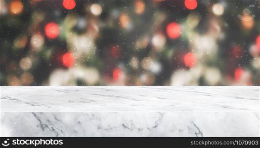 marble table top with abstract blur christmas tree red decor ball and snow fall background with bokeh light,winter Holiday backdrop,Mock up banner for display of product or promotion