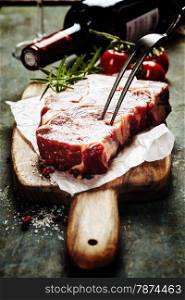 Marbled beef steak with a bottle of wine and vegetables on old wood background