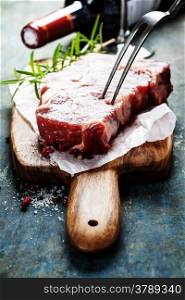 Marbled beef steak with a bottle of wine and wine glass on old wood background