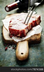 Marbled beef steak with a bottle of wine and wine glass on old wood background
