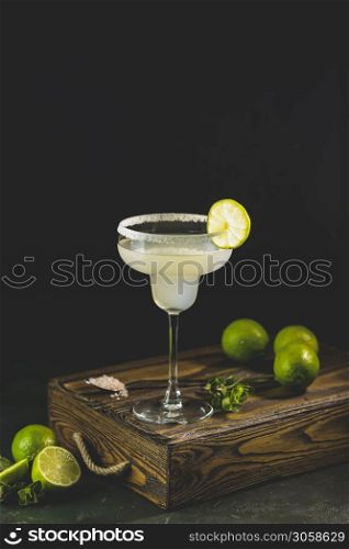 Margarita cocktail with lime and ice on minton dark wooden table with amazing backlight, copy space. Classic Margarita or Daiquiry Cocktail.