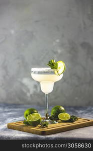 Margarita cocktail with lime and ice on minton light gray concrete table with amazing backlight, copy space. Classic Margarita or Daiquiry Cocktail.