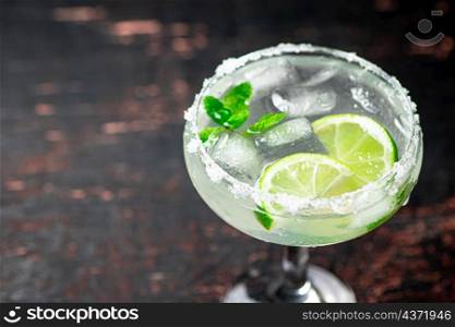 Margarita with mint and ice cubes. Against a dark background. High quality photo. Margarita with mint and ice cubes.