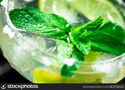 Margarita with mint and lime leaves. On a black background. High quality photo. Margarita with mint and lime leaves.
