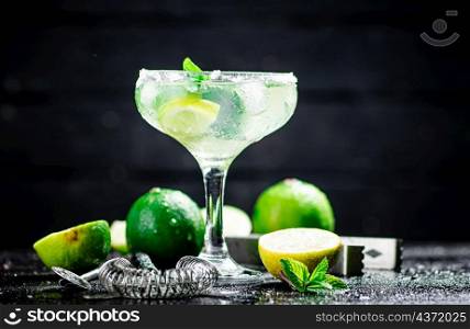 Margarita with mint and lime leaves. On a black background. High quality photo. Margarita with mint and lime leaves.