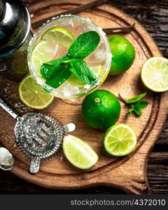 Margarita with pieces of lime. On a wooden background. High quality photo. Margarita with pieces of lime.