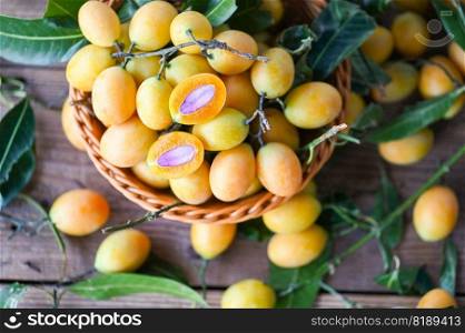 Marian plum fruit and leaves in basket on wooden background, tropical fruit Name in Thailand Sweet Yellow Marian Plum Maprang Plango or Mayong chid  