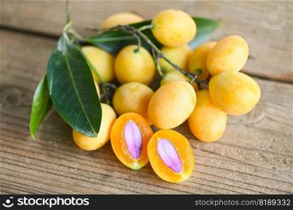 Marian plum fruit and leaves in plate on wooden background, tropical fruit Name in Thailand Sweet Yellow Marian Plum Maprang Plango or Mayong chid - top view