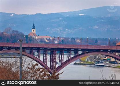 Maribor bridge on Drava river and church on the hill, Slovenia