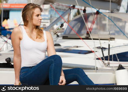 Marina place. Beauty fashionable blondie woman sitting in boats harbor. Travelling concept.. Attractive woman sitting on marina
