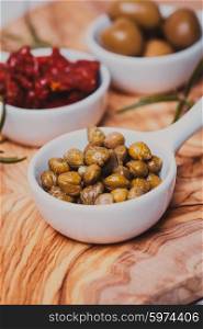 Marinated capers - in a white saucer on a board. Marinated capers