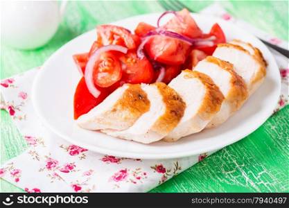 Marinated grilled chicken breasts served with fresh tomato salad, selective focus