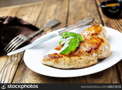 Marinated grilled healthy chicken breasts cooked on a summer BBQ and served with fresh herbs and lemon juice