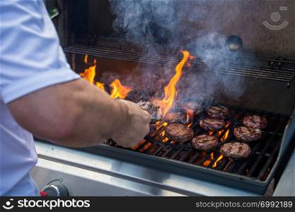 Marinated lamb joint and beef burgers cooking on a barbecue
