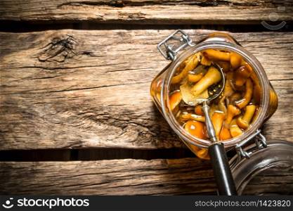 Marinated mushrooms in the jar. On wooden background.. Marinated mushrooms in the jar.