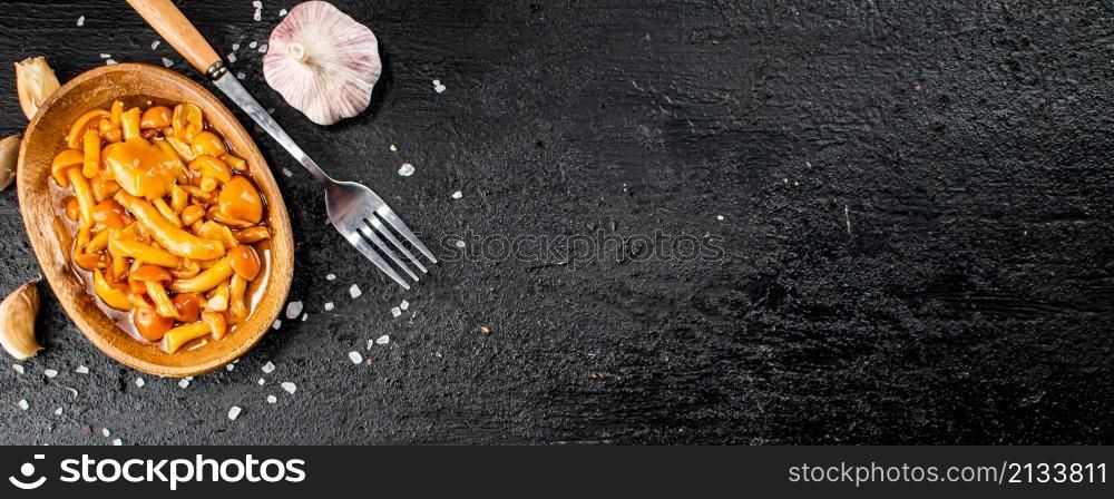 Marinated mushrooms on a plate with garlic and salt. On a black background. High quality photo. Marinated mushrooms on a plate with garlic and salt.