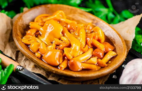 Marinated mushrooms on a plate with parsley. On a black background. High quality photo. Marinated mushrooms on a plate with parsley.