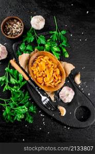Marinated mushrooms on a plate with parsley. On a black background. High quality photo. Marinated mushrooms on a plate with parsley.