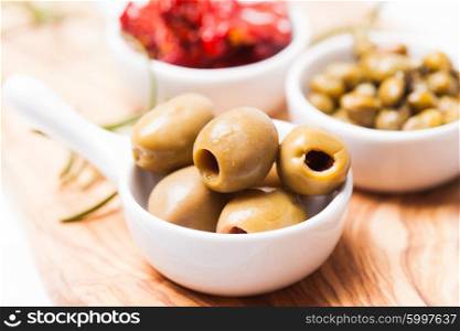 Marinated olives - in a white saucer on a board. Marinated olives close up