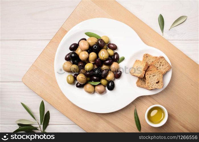Marinated olives in plate on wooden table. Tasty mediterranean food. Spanish tapa