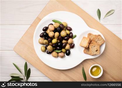 Marinated olives in plate on wooden table. Tasty mediterranean food. Spanish tapa