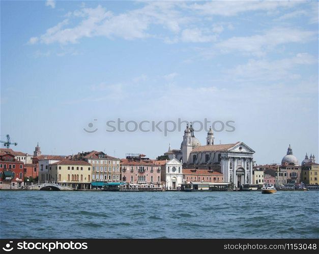 Marine cityscape to old historical part of Venice Italy with old-fashioned houses and temples in a sun summer day.. Old historical buildings and churches - view from water.