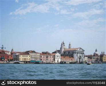 Marine cityscape to old historical part of Venice Italy with old-fashioned houses and temples in a sun summer day.. Old historical buildings and churches - view from water.