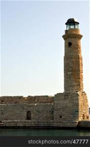 Marine lighthouse in a port of Crete with ramparts and the ocean.