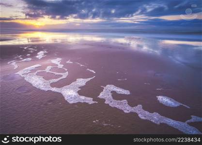 Maritime landscape at sunset with reflection of clouds in low tide water, Waddenzee, Texel, The Netherlands. Sunset over beach at North sea coast