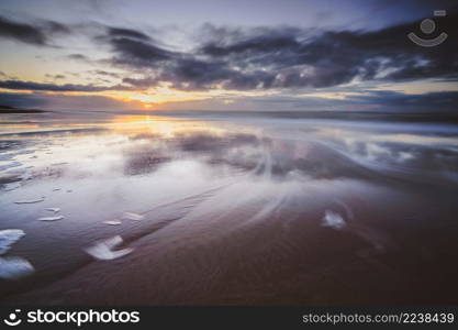 Maritime landscape at sunset with reflection of clouds in low tide water, Waddenzee, Texel, The Netherlands. Sunset over beach at North sea coast