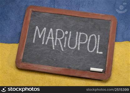 Mariupol white chalk text on a retro slate blackboard against paper abstract in color of Ukrainian national flag, blue and yellow, heroic city in Ukraine