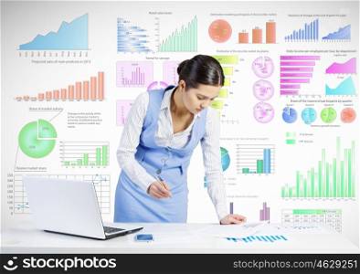 Market analysis and report. Businesswoman standing at table and writing with pen and infographs at background