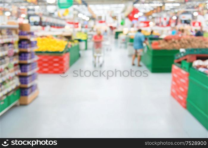 Market shop and supermarket interior in vegetable section with customers as blurred store background