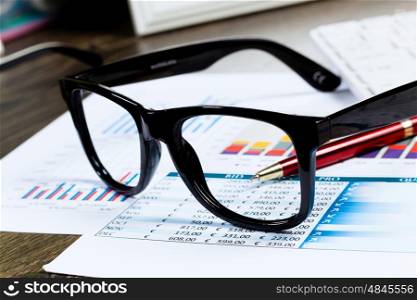Marketing report. Eye glasses lying on papers with graphs and diagrams