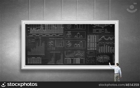 Marketing sales strategy. Rear view of businessman drawing infographs on chalkboard