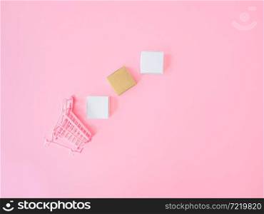 Marketing strategy or shopping concepts from trolley and product box on pink background. Top view