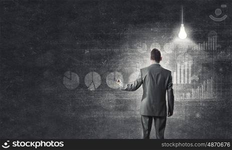 Marketing strategy. Rear view of businessman drawing marketing charts and graphs