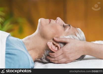 Marma therapy.  Beautiful senior woman lying on massage table and enjoying Ayurveda Facial treatment. . Marma Therapy. Ayurveda Head Massage, Shiro Abhyanga