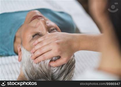 Marma therapy.  Beautiful senior woman lying on massage table and enjoying Ayurveda Facial treatment. . Ayurveda Facial Marma Massage