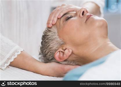 Marma therapy.  Beautiful senior woman lying on massage table and enjoying Ayurveda Facial treatment. . Marma Therapy. Ayurveda Face Therapy